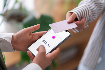Two people using NFC technology to make a payment with their mobile phones One phone shows the payment amount, demonstrating a cashless transaction