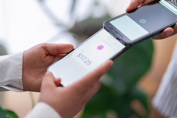 Two people engage in a digital payment transaction using their mobile phones The phones are close together, highlighting the ease of electronic transactions