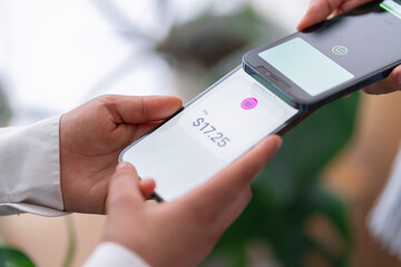 A close-up of a tap to pay mobile payment transaction between two people, with one phone displaying The scene emphasizes the simplicity and efficiency of digital payments