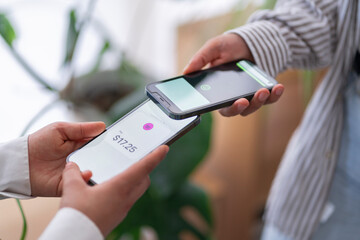 Two people engage in a digital payment transaction using their mobile phones The phones are close together, highlighting the ease of electronic transactions