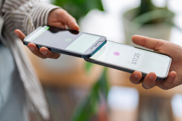 Two people engage in a digital payment transaction using their mobile phones The phones are close together, highlighting the ease of electronic transactions