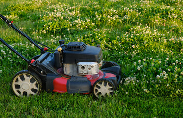 Lawn mower on green grass background. Petrol machine for cutting. Garden care. Electric equipment....