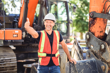 caucasian engineer with white helmet at work and having a mechanical shovel on the back