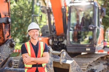 caucasian engineer with white helmet at work and having a mechanical shovel on the back