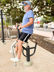 Obraz premium Attractive smiling retired man exercising outdoors with sports free equipment to keep fit. Cardio and muscle exercises for mature people. Athletic spirit concept