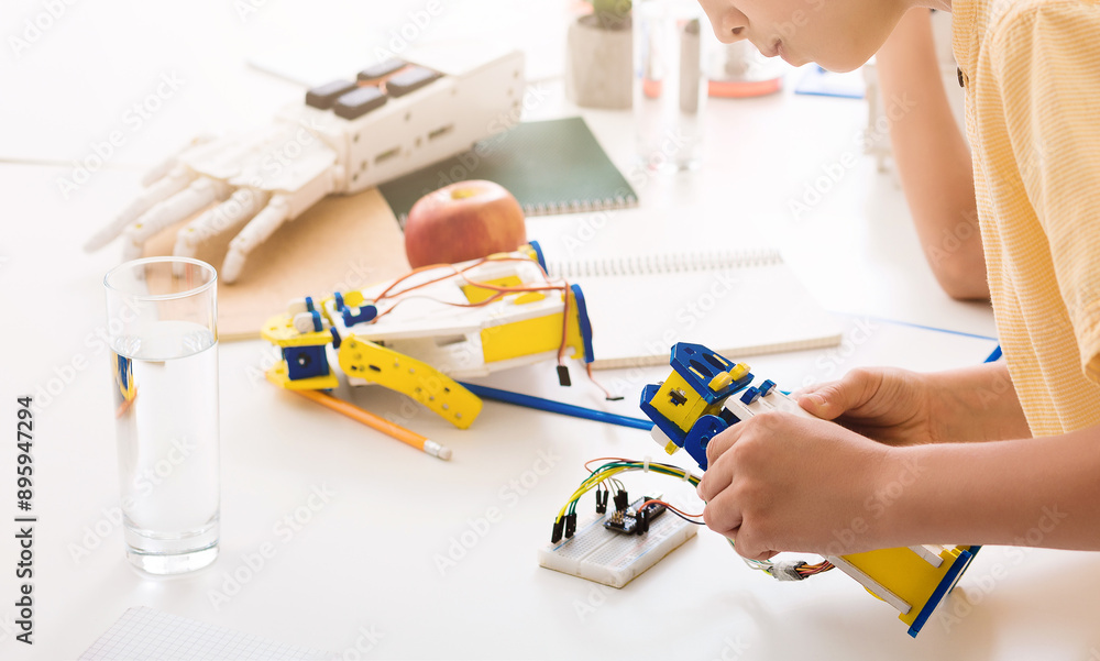 Aufkleber a young student sits at a desk, focusing intently on building a robotic hand. the hand is a bright y