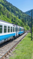 Fototapeta premium A blue passenger train travels along a track through a forest landscape. A red metal bridge is visible in the distance. The sky is bright blue with white clouds