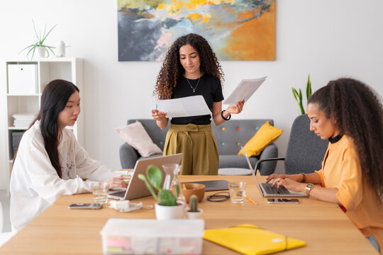 Young professionals engaged in teamwork and planning, discussing documents and ideas in a bright office setting, highlighting collaboration and productivity