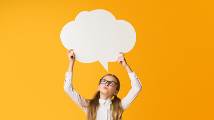 Thinking Of School. Pensive Little Schoolgirl Holding Speech Bubble Overhead On Yellow Background. Mockup, Copy Space