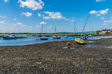 A view past boats down the Chichester estuary at Bosham, West Sussex at low tide in summertime