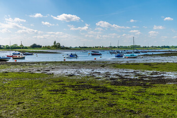 A view of boats moored in the Chichester estuary at Bosham, West Sussex at low tide in summertime