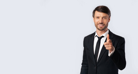 Hey, You. Smiling Businessman Pointing Finger At Camera Standing On White Background. Studio Shot, Free Space