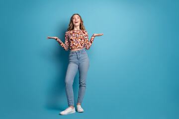 Full size photo of nice young girl hold empty space vs wear top isolated on blue color background