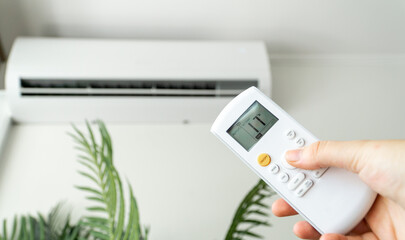 Person using a remote control to set a lower temperature in the room