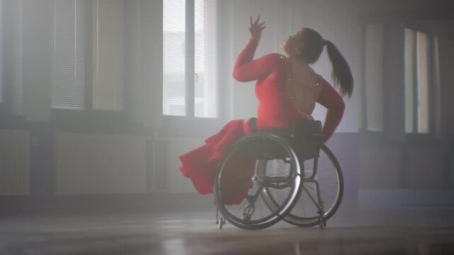 Female wheelchair dancer performing beautiful elegant choreography at a dance studio, full shot. Disability sport concept.