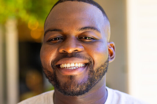 Smiling african american man enjoying time outdoors, close-up portrait with natural light