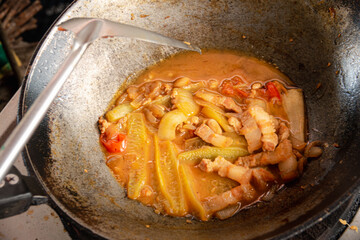 A pan of food is being cooked in a skillet. The food is a mix of vegetables and meat, and it is a stir fry