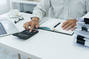 office employee works on desk, using calculator to manage financial documents and accounts,...