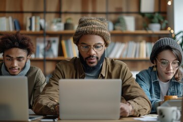 A group of three individuals working diligently on their laptops in a cozy library, exuding a warm atmosphere of concentration, collaboration, and productivity.