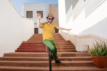 Young Hispanic man having a fun time sliding down the railing of a staircase on the street