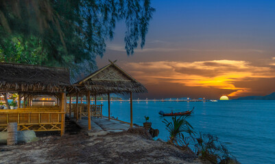 Colourful Skies Sunset over Rawai Beach in Phuket island Thailand. Lovely turquoise blue waters, lush green mountains colourful skies and beautiful views of long tail Boats