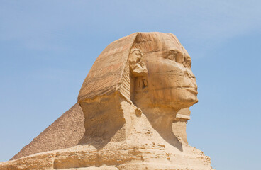 Great Sphinx against pyramides and blue sky, Giza, Egypt