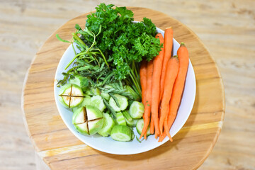 Healthy food: Fresh vegetables rosemary, carrots, brinjal and cucumber in a white ceramic plate.
