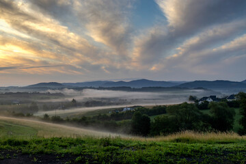 Fototapeta premium Landscape with backlit clouds and mists over the hills just after sunrise
