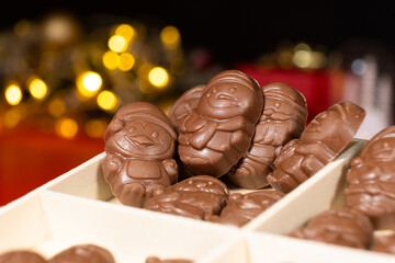Chocolates in the shape of Christmas figures on the background of a flashing garland
