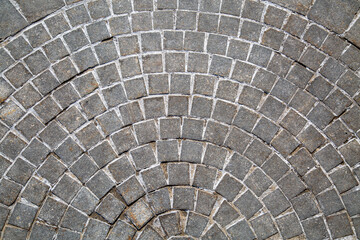 The sidewalk is made of natural stone paving stones of a square shape in the form of a fan or diverging rays. Texture backgrounds for graphic design.
