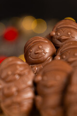 Chocolates in the shape of Christmas figures on the background of a flashing garland