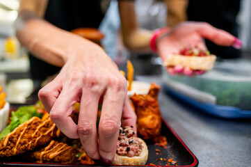 Close-up of woman chef hands assembling a sandwich on kitchen