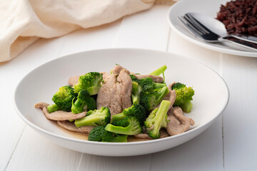 Stir fried broccoli with pork tenderloin fillet in white plate.Thai Healthy food for low fat diet menu.