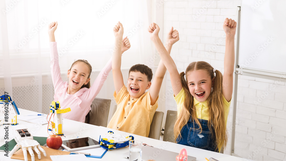 Poster three children, two girls and one boy, sit at a table with their arms raised in victory. they have c