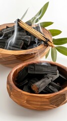 Obraz premium Three wooden bowls filled with different sizes of charcoal pieces. A plume of smoke rises from the bowl on the left