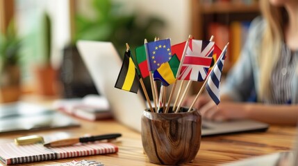 Close-up of international flags on a desk, with a blurred woman foreign language teacher working at a laptop, Foreign language online course, class, e-education concept.