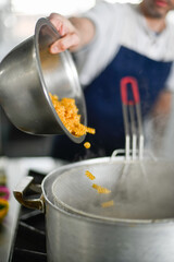 man puting pasta on boling water