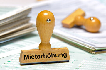 Ein Holzstempel ist beschriftet mit dem Aufdruck: Mieterhöhung