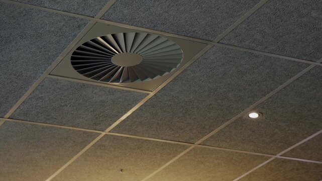 A contemporary ceiling fan set into a textured drop ceiling, highlighting modern office design and efficient air circulation features. Modern Ceiling Fan Integrated Into Textured Ceiling at Office