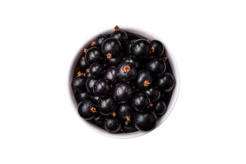 Ripe blackcurrant berries in droplets of water in a ceramic bowl