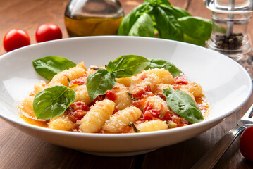Deliziosi gnocchi di patate con pomodoro, basilico, olio di oliva e parmigiano, cibo italiano, dieta mediterranea 