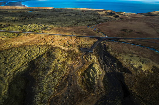 Aerial view of coastal road along rugged terrain and ocean, Hellnar, Arnarstapi, Iceland.