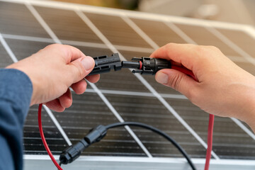 Close up of technician's hands connecting mc4 connectors over the solar panel.