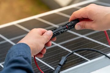 Close up of technician's hands connecting mc4 connectors over the solar panel.