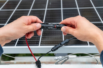 Close up of technician's hands connecting mc4 connectors over the solar panel.