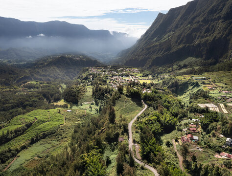 Aerial view of fog-covered Cirque de Salazie with remote village and lush greenery, Salazie, Reunion.