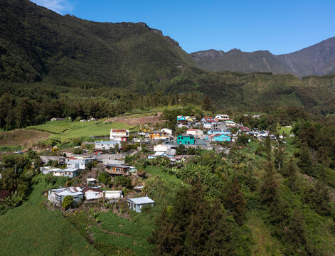 Aerial view of lush and tranquil Creole Village with mountain range and plateau, Cirque de Salazie, Reunion.