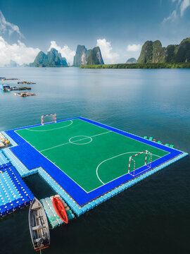 Aerial view of floating soccer field surrounded by mountains and boats, Mueang Phang Nga, Thailand.