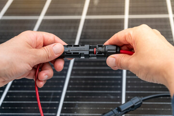Close up of technician's hands connecting mc4 connectors over the solar panel.