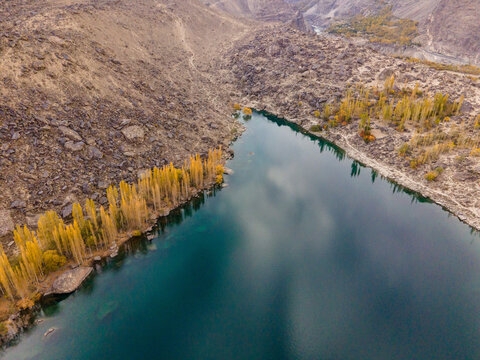 Aerial view of serene lake surrounded by majestic mountains and vibrant foliage, Kashmir region, Pakistan. - Powered by Adobe